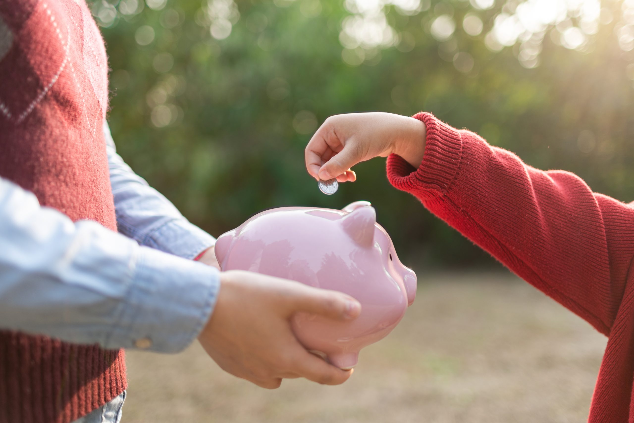 child putting a coin in a piggy bank